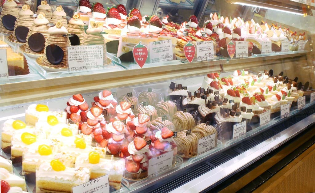 冷蔵ショーケースに並んだモンブラン、いちごのショートケーキ、チョコレートケーキなど生ケーキと洋菓子